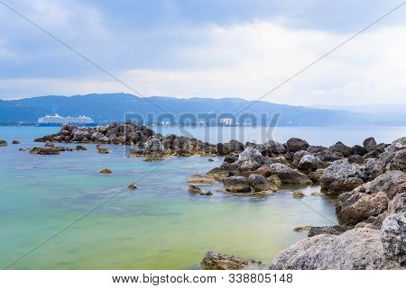 Montego Bay, Jamaica - March 19 2018: Mein Schiff 6 Cruise Ship Docked Beyond Large Ocean Rocks In M