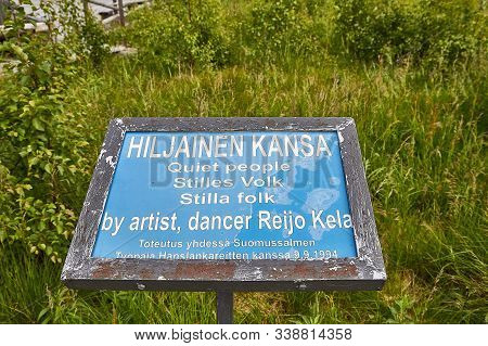 Suomussalmi, Finland - July 24, 2019: A Sign Near The Field With The Group Of Objects In People Clot