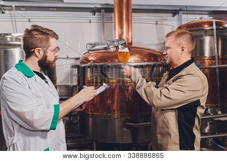 Mature Man Examining The Quality Of Craft Beer At Brewery. Inspector Working At Alcohol Manufacturin