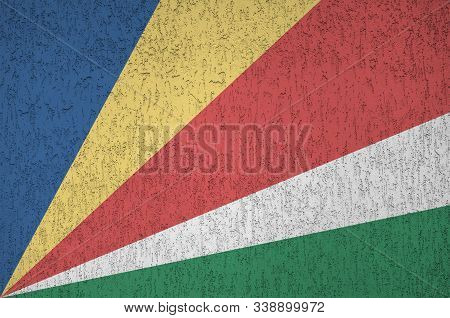 Seychelles Flag Depicted In Bright Paint Colors On Old Relief Plastering Wall. Textured Banner On Ro