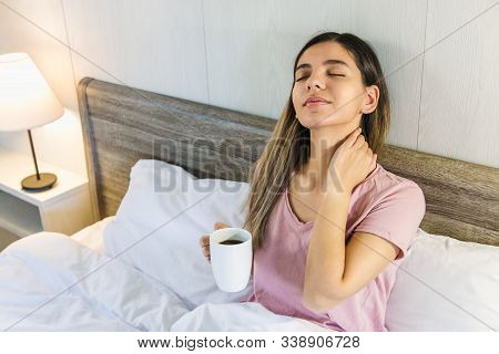 Woman Sitting On Bed With Eyes Closed Holding A Cup Of Coffee Or Tea