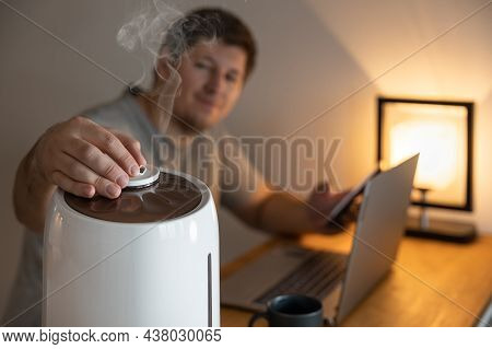 Handsome Man Turns The Nozzle Of White Air Humidifier. Humidification Of Dry Air. Selective Focus On
