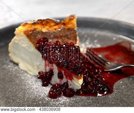 A Slice Of Cheesecake With Cranberry Sauce On A Large Gray Plate