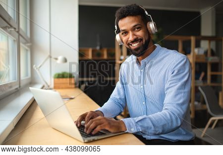 Young African-american Teacher With Headset And Laptop Indoors In Staffroom Looking At Camera.