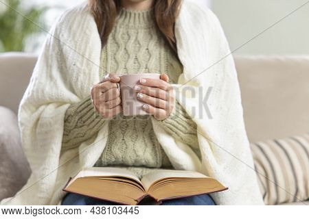 Young Woman Reading Book And Enjoying Hot Coffee At Home
