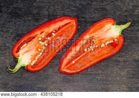 Two Halves Of The Fresh Red Bell Pepper Cut Lengthwise On The Dark Surface, Top View
