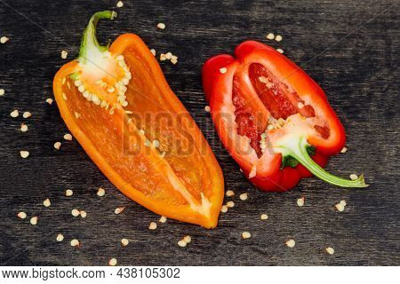 Two Halves Of The Fresh Bell Peppers Red And Orange Colors Cut Lengthwise Lie On The Dark Surface Am