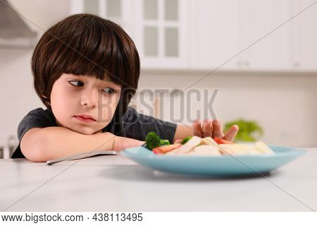 Cute Little Boy Refusing To Eat Dinner In Kitchen