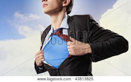 Image of young businessman showing superhero suit underneath his shirt