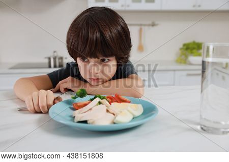 Cute Little Boy Refusing To Eat Dinner In Kitchen