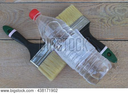 A Bottle Of Acetone - Two Paintbrushes And Gloves In The Background - Wooden Background - Constructi