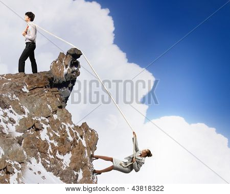 Imagem de busionessman e empresária puxando a corda no topo da montanha