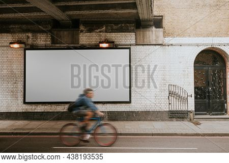 Biker biking past billboard with design space on the street of London