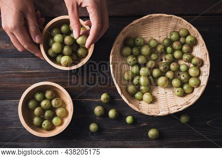 Wild Indian Gooseberry Or Amla In A Bamboo Basket And Bowl With Hand On Wooden Background, Fruit Tre