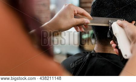 Hairdresser trimming hair of the customer at a barbershop