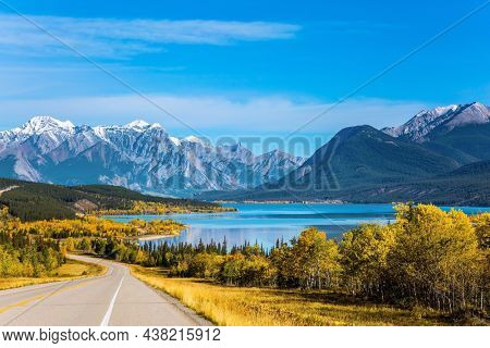 Stunning Abraham Lake in the Canadian Rockies.  The yellow foliage of birches and aspens is mixed with green conifers. Asphalt highway leads to Abraham Lake