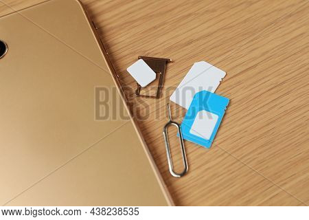 Sim Cards, Mobile Phone And Ejector Tool On Wooden Table, Flat Lay