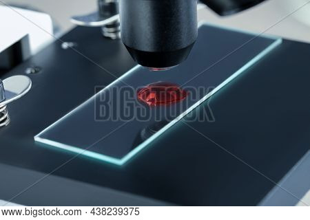 Glass Slide With Sample Of Red Liquid Under Microscope In Laboratory, Closeup