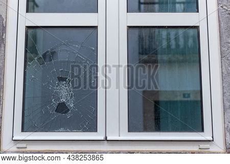 Cracked Glass In A Plastic Vacuum Window Frame. A Damaged Window Due To Vandalism, Natural Disaster,