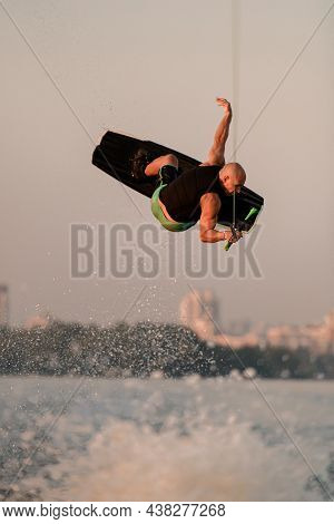 Active Strong Man Jumping And Flips On Wakeboard Over Splashing Wave