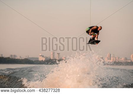 Awesome View Of A Muscular Man With A Wakeboard While Jumping Over The Wave