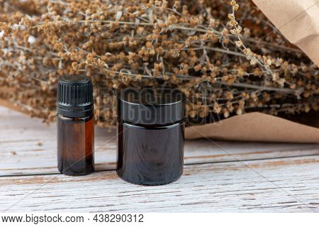 Dried Wormwood Herb, Artemisia Absinthiu, And Glass Bottles On Wooden Table.