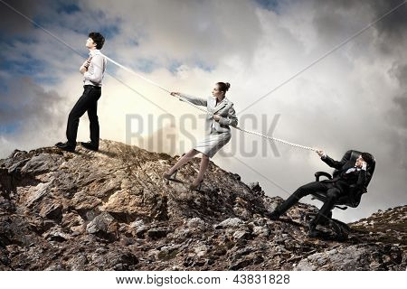 Imagem de três empresários puxando a corda no topo da montanha