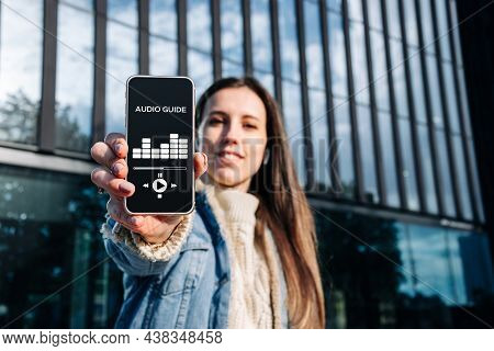 Audio Guide Online App On Digital Mobile Smartphone. Happy Young Student Woman Holding Phone Listeni