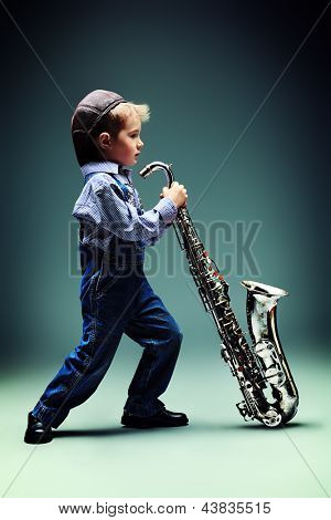 Retrato de um jazzman de menino pequeno bonito tocando seu saxofone. Estilo retrô.