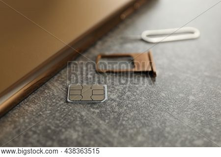 Sim Card, Mobile Phone, Tray And Ejector Tool On Grey Table, Closeup
