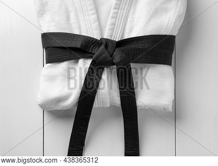 Martial Arts Uniform With Black Belt On White Wooden Background, Top View