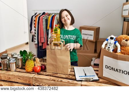 Brunette woman with down syndrome putting donated food in paper bag at donations stand