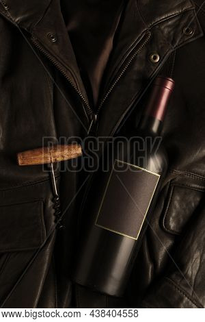 Wine bottle and corkscrew on a leather bomber jacket. Flat lay with copy space.