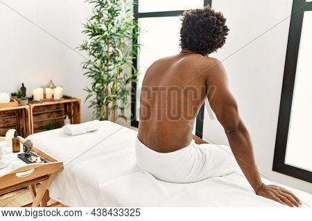 Young african american man sitting on massage board at beauty center