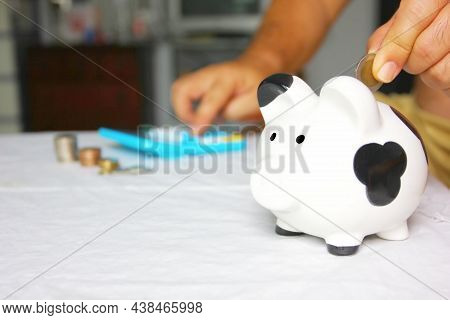 Man Putting Coin In To Piggy Bank While Left Hand Using Calculater , Saving Concept