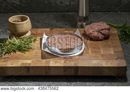 Raw Minced Meat Cutlets With Herbs And Spices On A Wooden Board On A Dark Background