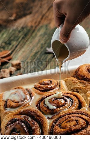 Sinnabon Buns Rolls. Woman's Hand Spreading Vanilla Cream.