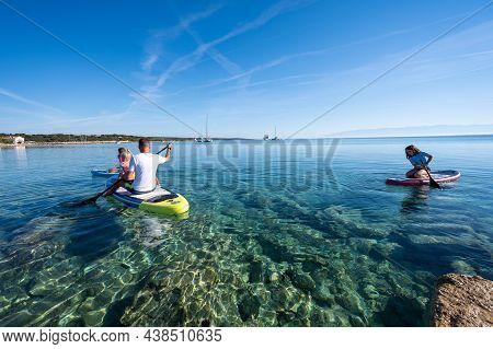Happy Family On Sup Stand Up Paddle On Vacation. Active Family Riding Sup Boards And Paddling In The