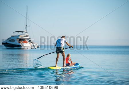 Father And Daughter Riding Sup Stand Up Paddle On Vacation.
