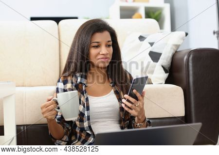 Portrait Of Latino American Woman Using Smartphone And Laptop For Spare Time. Enjoying Weekend At Ho