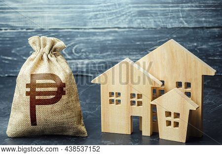 Philippine Peso Money Bag And Figurines Of Residential Buildings. Property Tax. Municipal Budgeting.
