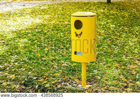 Yellow Dog Waste Bin On The Background Of Park Greenery