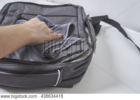 Cleaning Backpack With Washcloth. A Person Wipes Off Dirt Or Dust From The Outside Of The Bag. Wipin