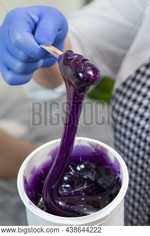 Spa Procedure. Closeup Of Beautician Hands  With Liquid Purple Wax Composite During Waxing Or Sugari