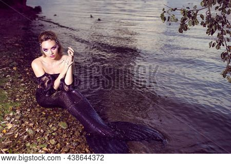 Alluring Mermaid Posing Near Seashore On Rocks While Wearing Artistic Makeup And Facial Strassses An