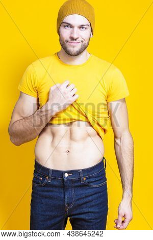 Positive Caucasian Handsome Man In Yellow Tshirt Posing In Warm Hat Over Yellow Background While Pul
