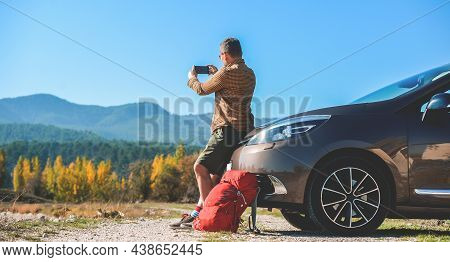 Man Travel By Car And Making Photo And Video On Mobile Phone. Break Between Road Trip. Mobile Phone 