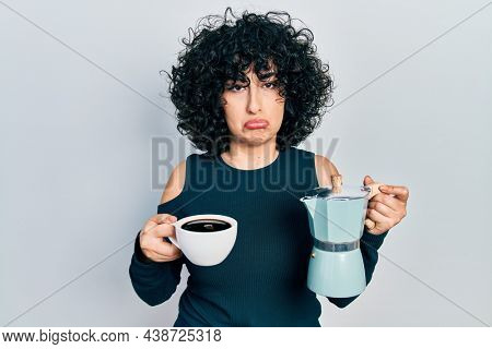Young middle east woman holding italian coffee maker depressed and worry for distress, crying angry and afraid. sad expression. 