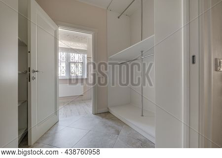 Rows Of Shelves And Clothes Hangers In Empty Big Wardrobe Room In Modern Apartment Or Hotel