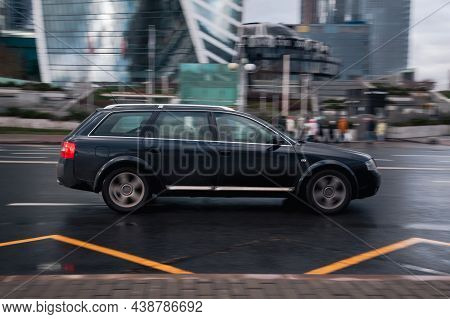 Car Audi A6 Driving On The Wet Road. Dark Green Old Estate Car Rushes Along The Street On High Speed